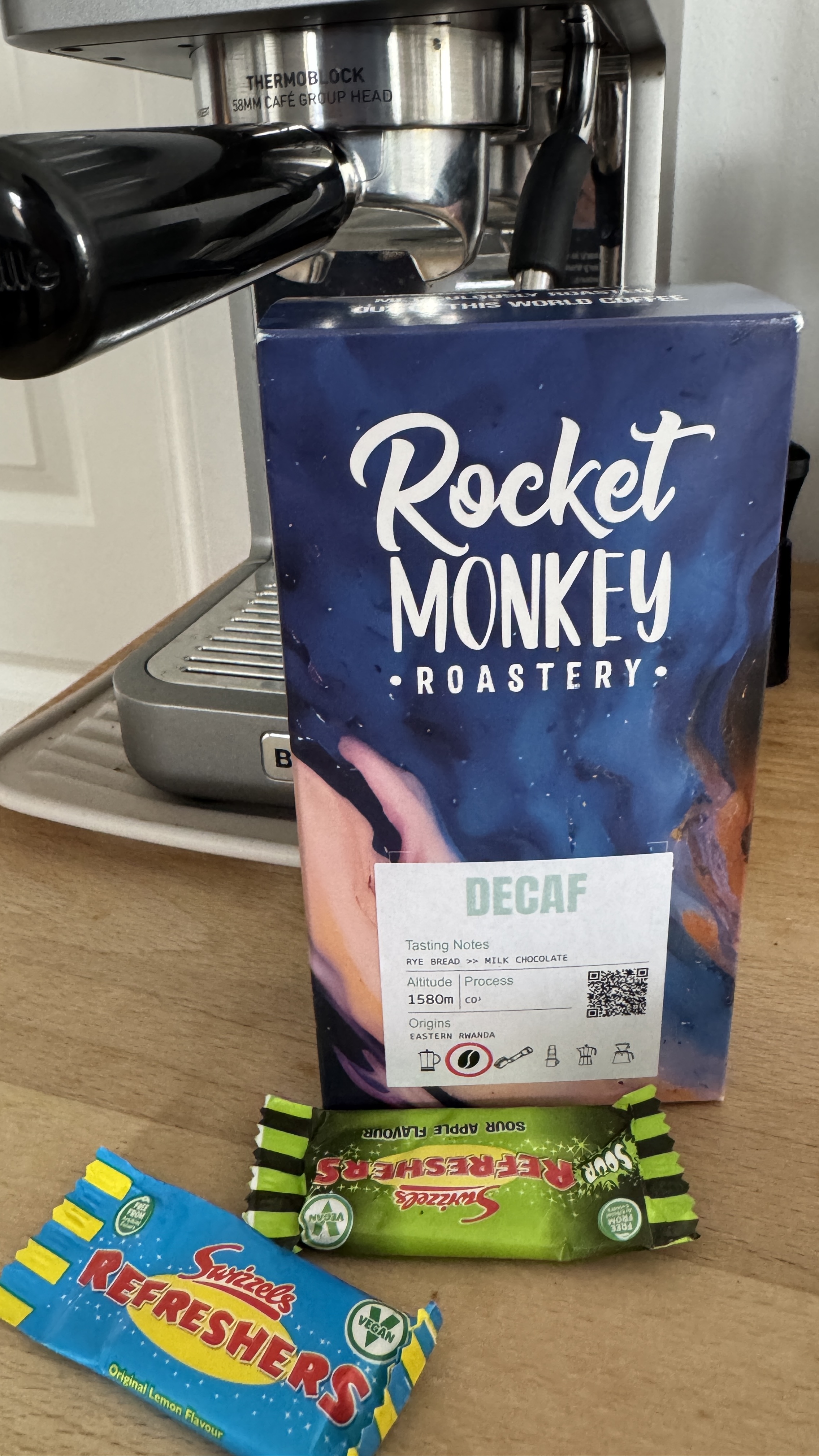 Bag of Rocket Monkey decaf coffee in front of an espresso machine